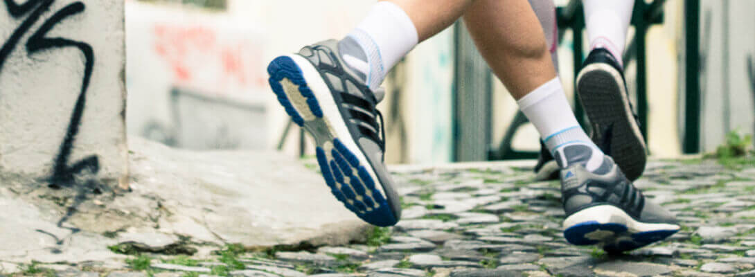 Läufer mit Laufsocken joggt durch die Stadt - Fokus auf die Füße mit Produkt