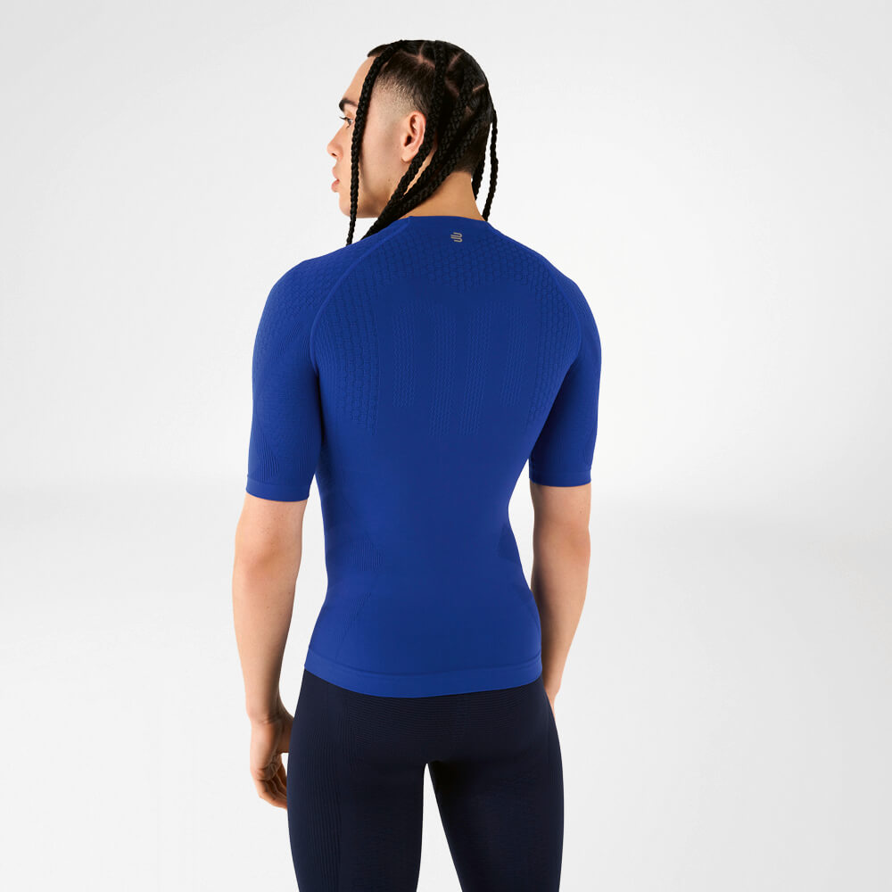  Ein Mann in einem blauen Kompressionsshirt steht mit dem Rücken zur Kamera und schaut über seine Schulter.