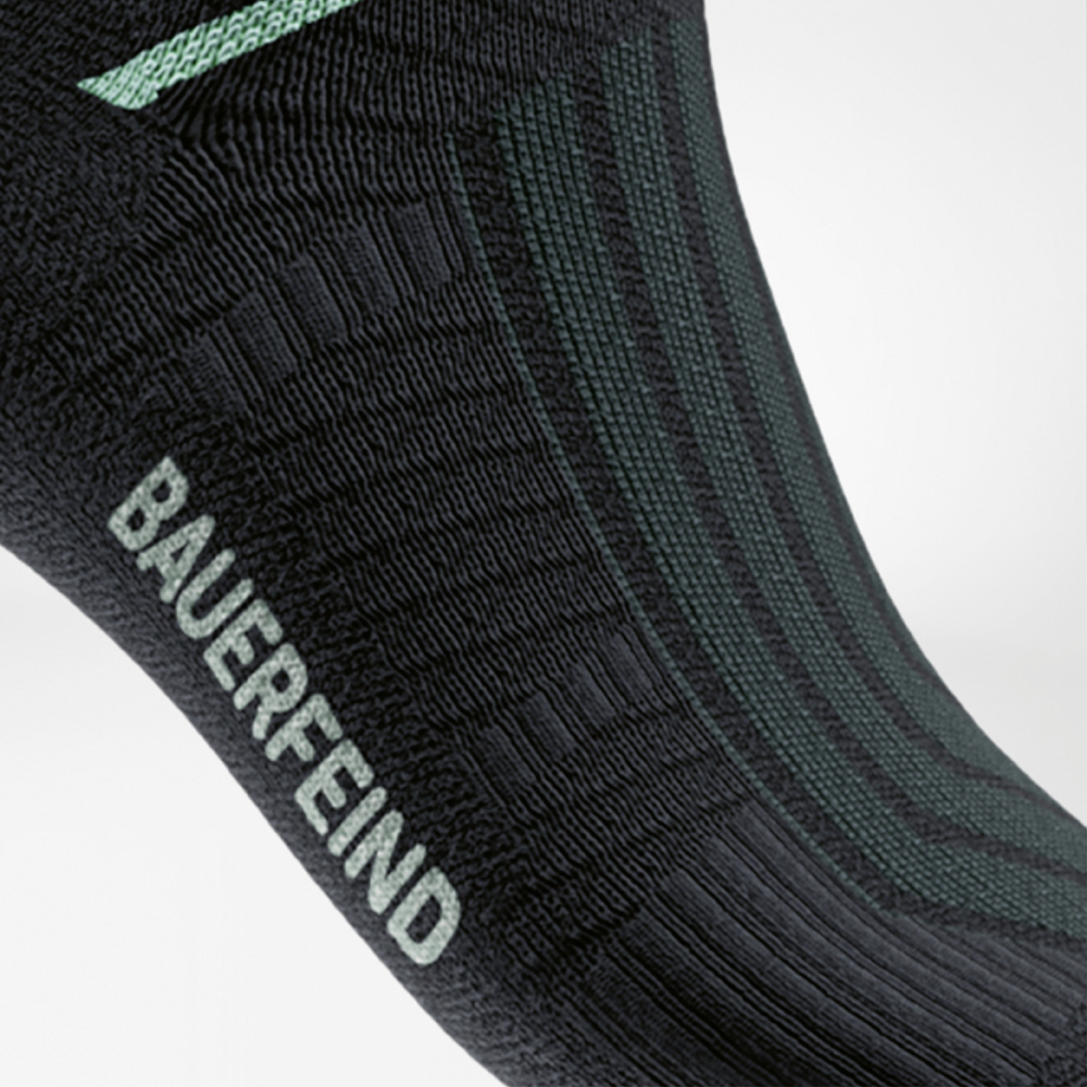 Detailaufnahme der Run Performance Midcut Socks in Schwarz mit mintfarbenem Arch-Lift-Element. Die Aufnahme hebt die spezielle Kompressionszone am Fußgewölbe hervor, die für Stabilität und Halt sorgt.