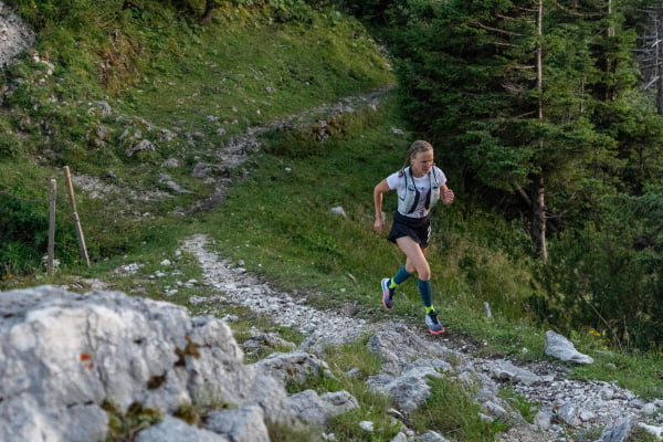 Läuferin hat Trail Run Socken an und joggt über ein steiniges, hügeliges Gelände im Wald