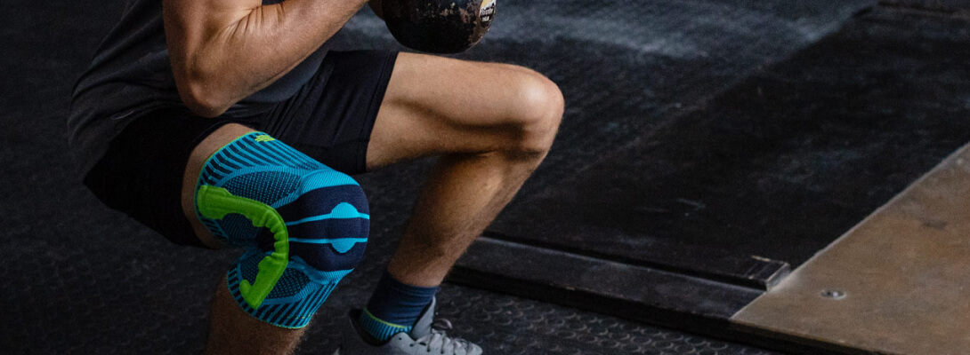 Kniebandage beim Fitness Sportler im Fitnessstudio in der Kniebeuge trägt eine Kniebandage für den Sport