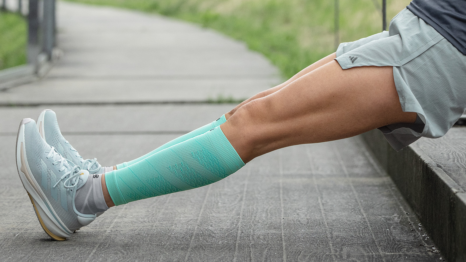 Läuferin in rosa Laufsocken stretcht ihre Waden am Boden sitzend und lächelt