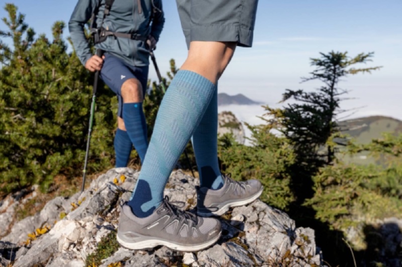 Frau mit grünen Wandersocken tritt auf einen Felsen in der Dämmerung