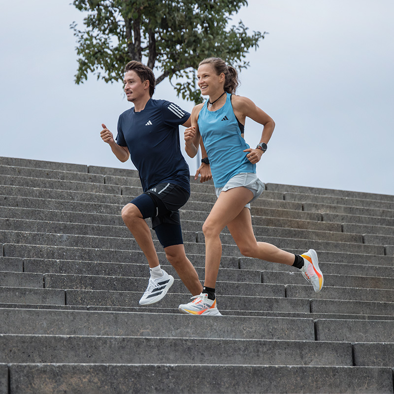 Lauftraining ist nicht immer ein reines Zuckerschlecken, in der Gruppe aber umso motivierender Zwei Läuferinnen und ein Läufer laufen eine Straßenbahnlinie in einer Stadt hinauf