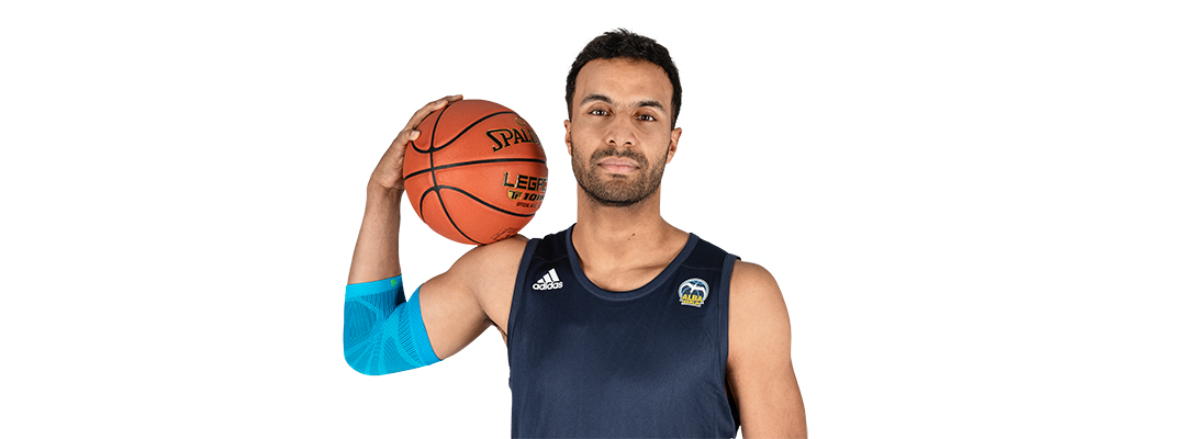 Ellenbogensleeve beim Basketballspielen Mann mit Basktetball trägt einen Sportsleeve für den Ellenbogen