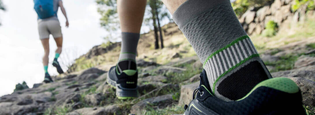 Wanderer mit Trekkingsocken laufen einen Berg hoch	 Zoom auf die Socken