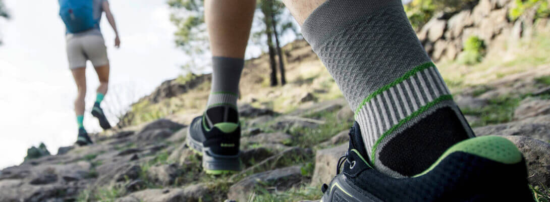 Trekkingsocken grau Detailaufnahme Outdoor Wanderer mit Trekkingsocken laufen einen Berg hoch Zoom auf die Socken