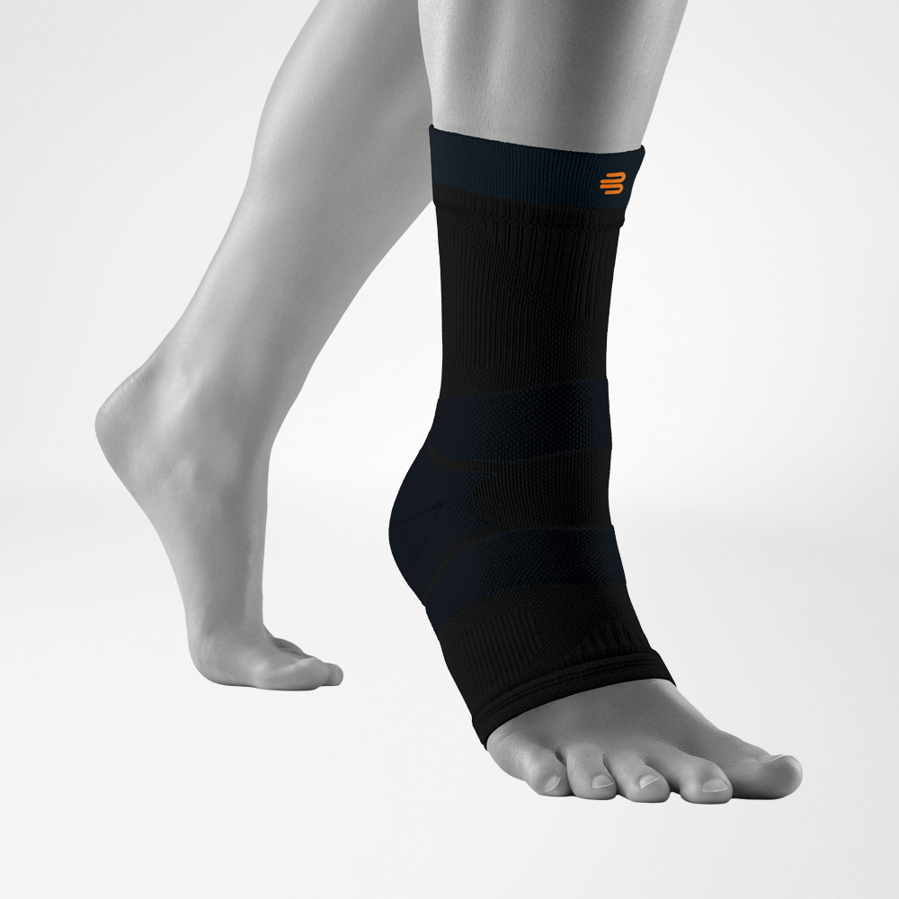 Freigestellte Darstellung der Outdoor Compression Ankle Support in Schwarz am Fuß eines Modells. Die Knöchelbandage liegt eng an und zeigt die anatomische Passform