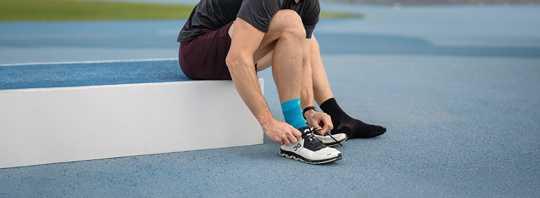 Anziehen einer Sprunggelenkbandage Läufer mit Compression Ankle Support beim Schuhe anziehen