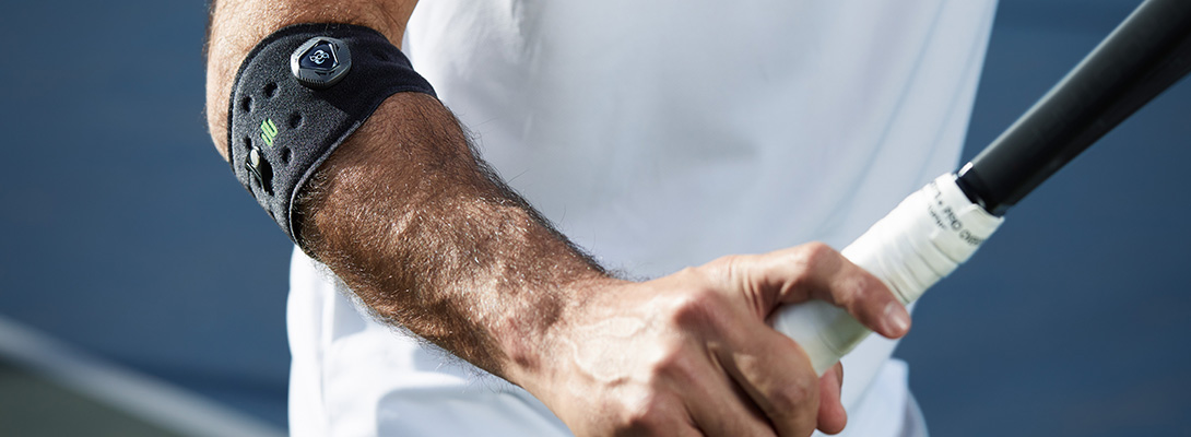Badmintonspieler der eine Ellenbogenspange zur Entlastung bei Tennisellenbogen trägt
