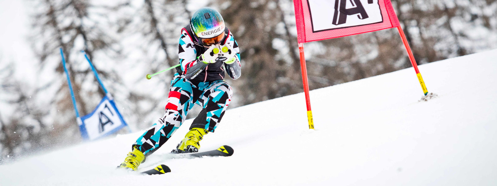 Der Riesenslalom verbindet anspruchsvolle Schwünge mit der Beschleunigung einer Abfahrt Skiläuferin im blau-weiß-roten Rennanzug geht nach dem Passieren eines großen Tores in die Abfahrtsposition