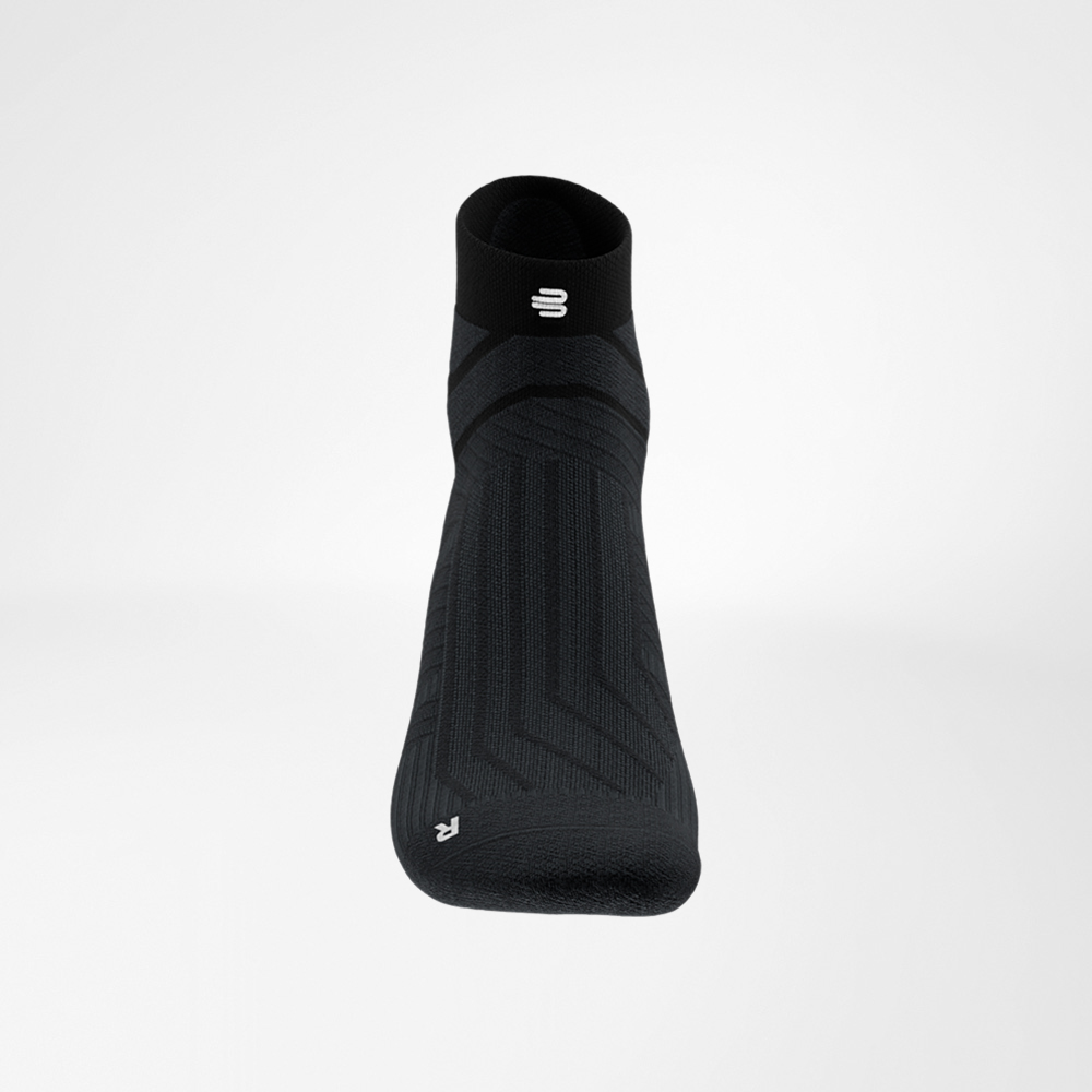 Detailansicht des Schaftes mit Logo Nahaufnahme des Schaftbereichs der schwarzen Run Performance Low Cut Socke von Bauerfeind, mit eingearbeitetem weißen B-Logo und feiner Rippstruktur.