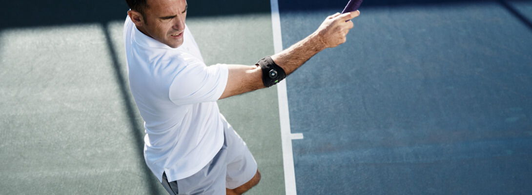 Tennisspieler der eine Ellenbogenspange zur Entlastung bei Tennisellenbogen trägt