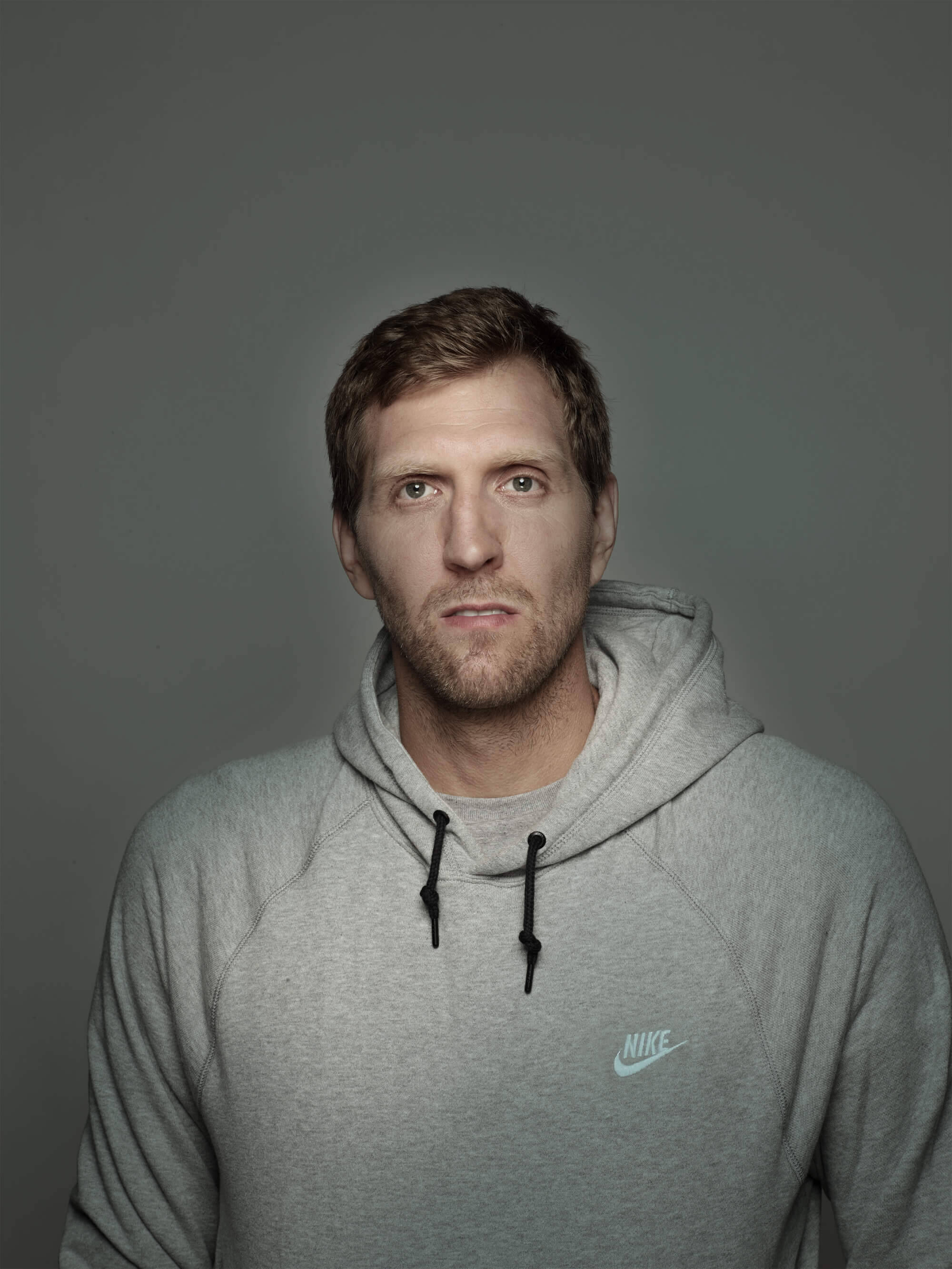 Portrait von Dirk Nowitzki im grauen Hoodie vor grauem Hintergrund