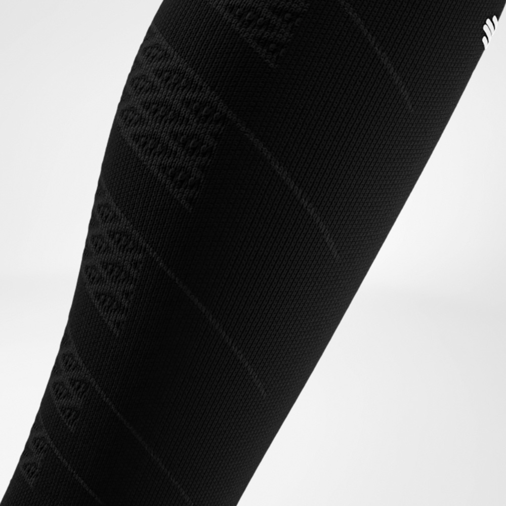 Nahaufnahme eines schwarzen Run Performance Compression Sleeves am Unterschenkel, das durch die feine Strickstruktur gezielte Kompression bietet und die Wadenmuskulatur beim Laufen unterstützt.