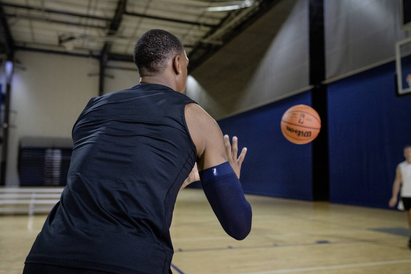 Basketballer mit blauem Armsleeve in Sporthalle erwartet einen Ball	 der ihm von einem anderen Spieler zugeworfen wird