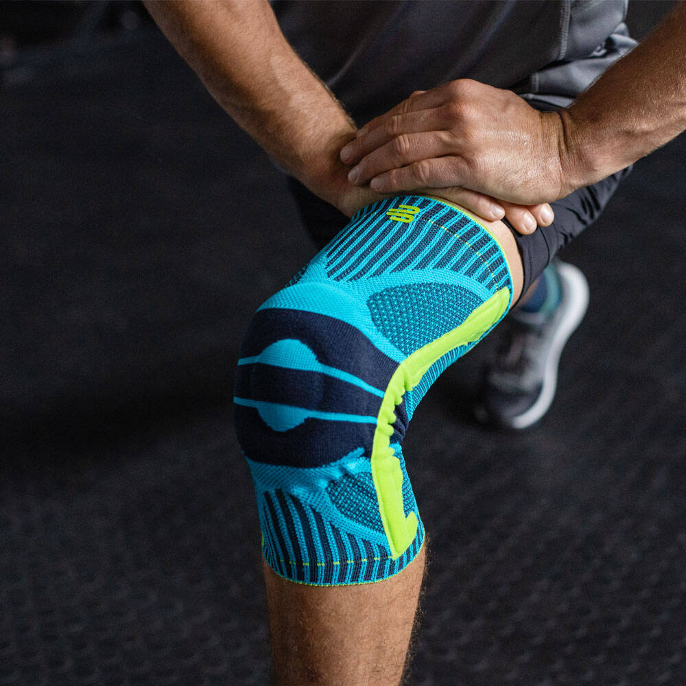 Sports Knee Support für Squats - Fitness Training Mann beugt sein Knie und trägt dabei eine Sports Knee Support