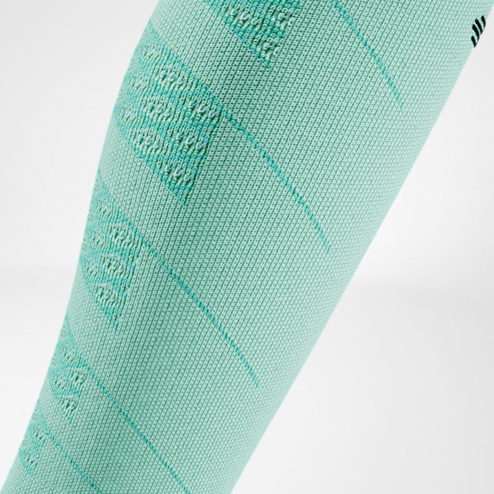 Nahaufnahme eines mintgrünen Run Performance Compression Sleeves am Unterschenkel, das durch die atmungsaktive Strickstruktur für eine leichte und angenehme Kompression sorgt.