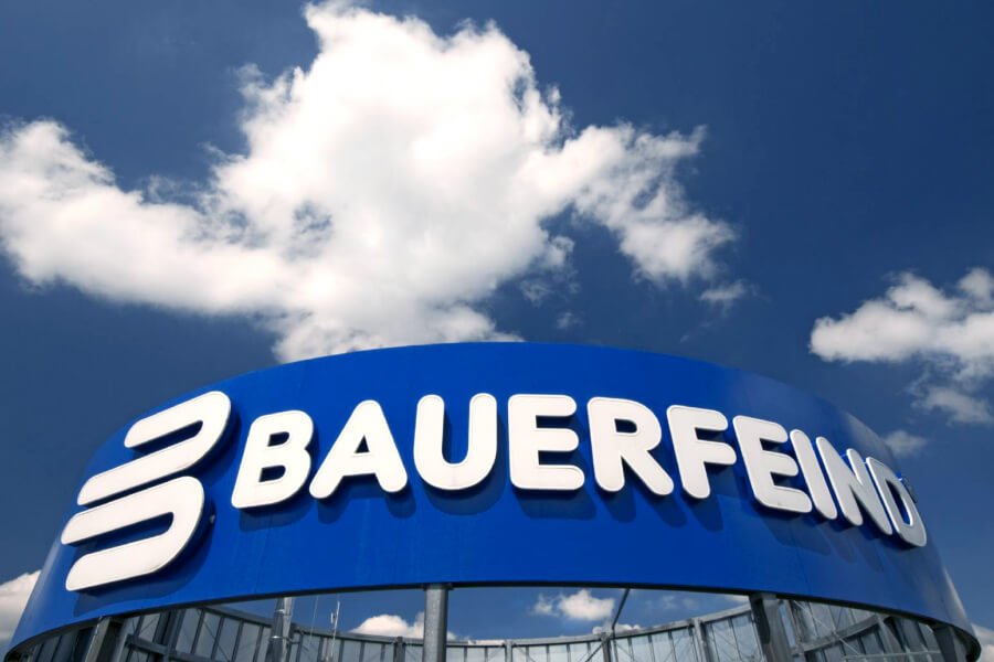 Die Bauerfeind Firmenzentrale in Zeulenroda-Triebes Bauerfeind Schriftzug auf blauem Untergrund auf dem Dach eines Hochhauses	 darüber blauer Himmel mit einer Wolke