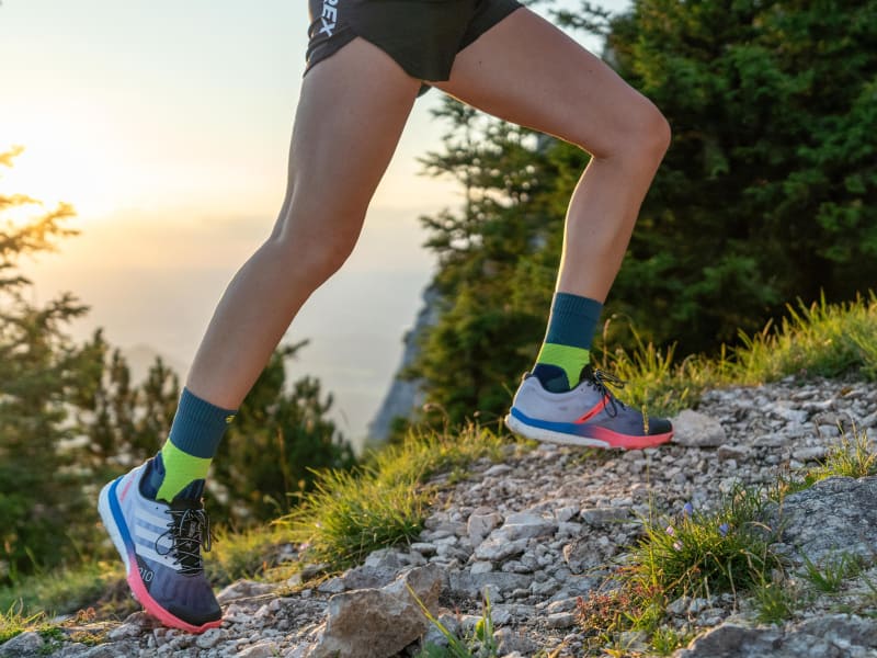 Mittellange Trail Run Socks Läuferin mit mittellangen Trail Run Socks läuft einen Berg hoch