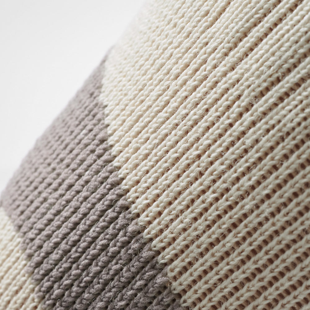 Detailaufnahme der sandfarbenen Kniebandage mit grauem Strickmuster. Das Material zeigt die dichte, elastische Struktur, die für gleichmäßige Kompression und hohen Komfort bei Outdoor-Aktivitäten sorgt.