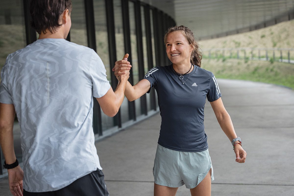 Gerade beim anstrengenden Marathontraining ist es wichtig, einfach mal in Ruhe den Sonnenuntergang zu genießen Frau im sommerlichen Laufoutfit sitzt auf dem Boden und blickt dem Sonnenuntergang entgegen