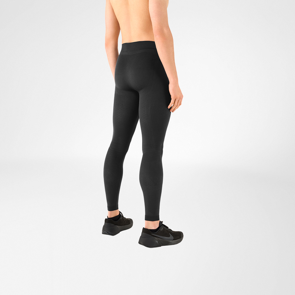 Zu sehen ist ein Ausschnitt eines oberkörperfreien Mannes, der schwarze Sportschuhe und eine anthrazitgraue Kompressionshose trägt. Er steht dabei seitlich mit dem Rücken zur Kamera
