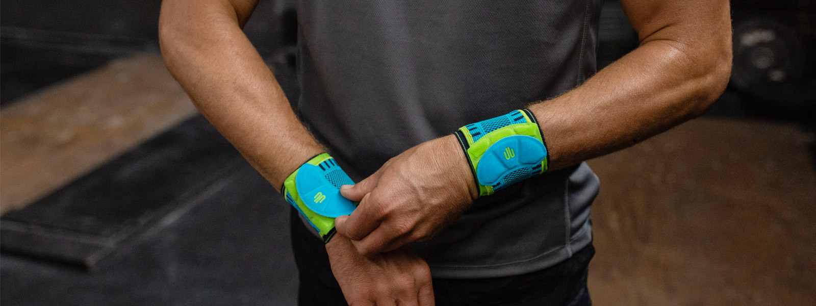 Sitzt wie Du es willst: Die Sports Wrist Strap mit individuell einstellbarem Gurt Mann in Fitnessraum zieht eine seiner Handgelenksbandagen zurecht