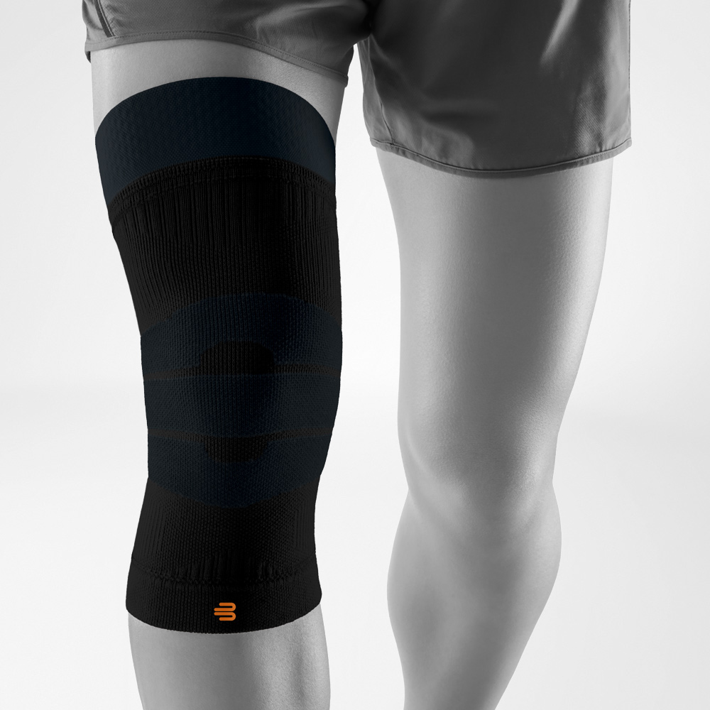 chwarze Kniebandage für Outdoor-Aktivitäten am Bein getragen, bietet gezielten Halt und Kompression für das Knie bei Sport und Bewegung im Freien.