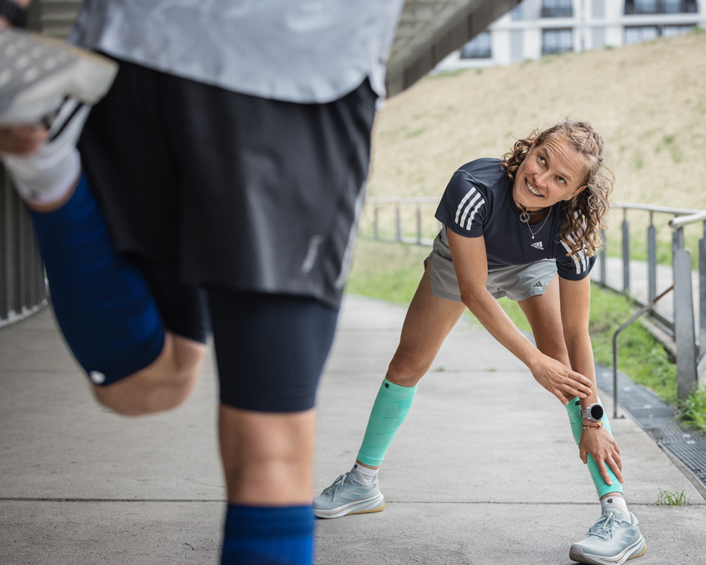 Das Training entspannt und farbenfroh genießen - Run Performance Compression Socks pink Läuferin mit lila Laufsocken lehnt sich in der Altstadt von Lissabon an eine Mauer