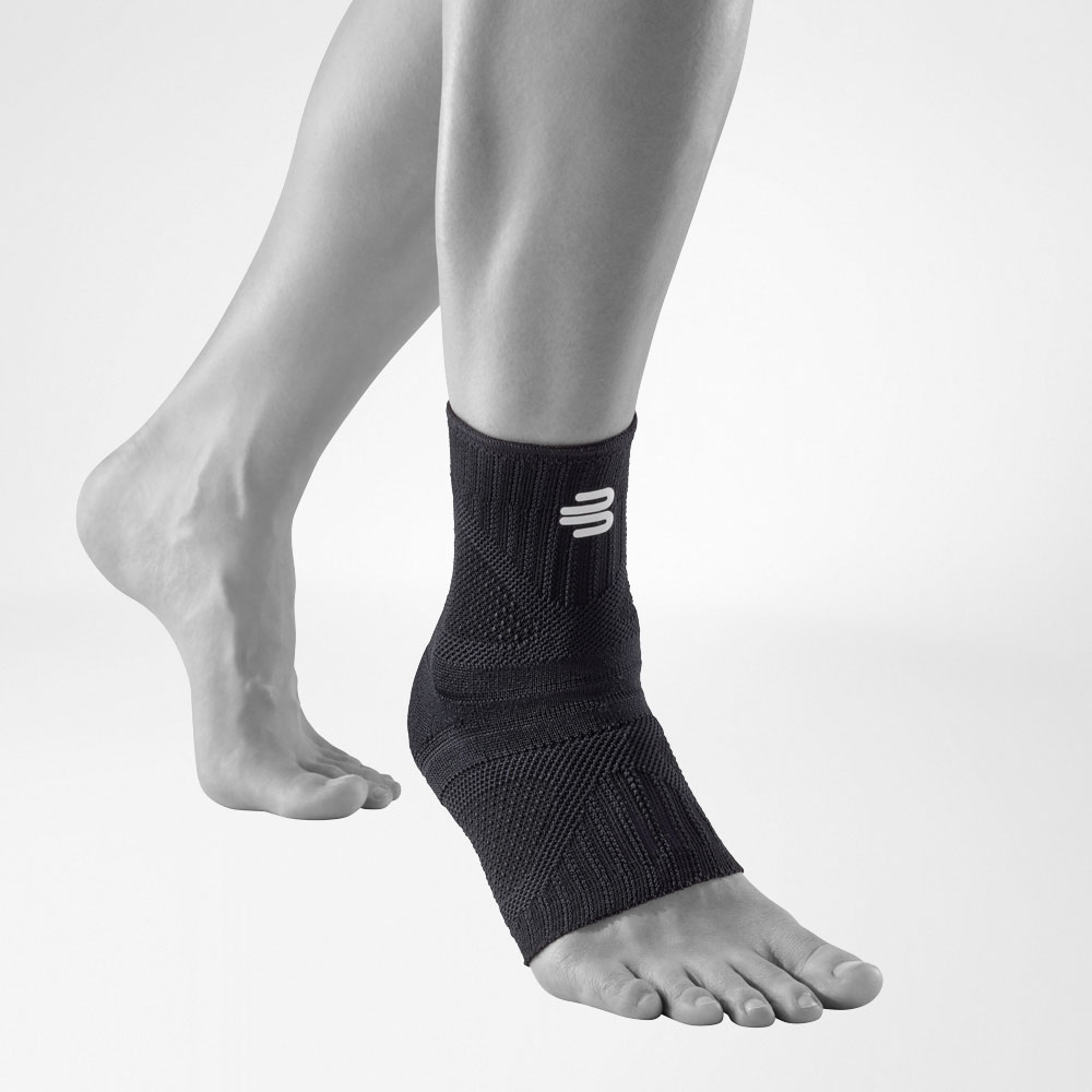 Sprunggelenkbandage allblack Vorderansicht schräg Vordere Komplettansicht der allblack-farbenen Ankle Support Dynamic am stilisierten grauen Bein