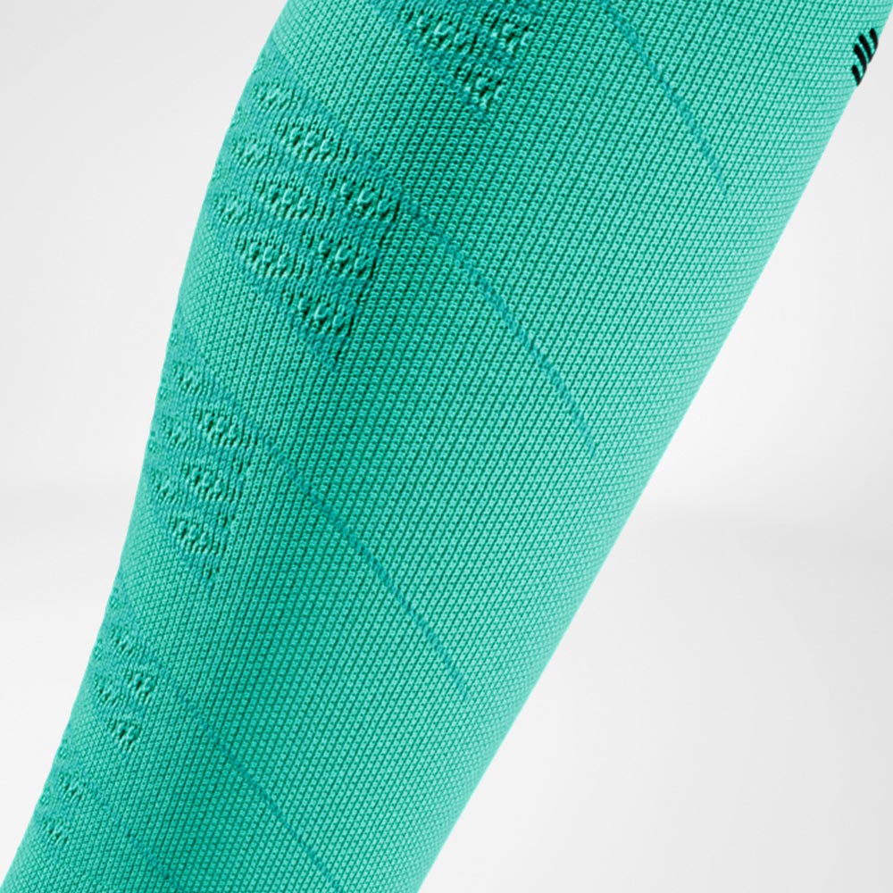 Detailaufnahme eines grünen Run Performance Compression Sleeves am Unterschenkel, mit deutlich sichtbarer Strickstruktur für gleichmäßige Kompression und Unterstützung bei sportlicher Belastung.