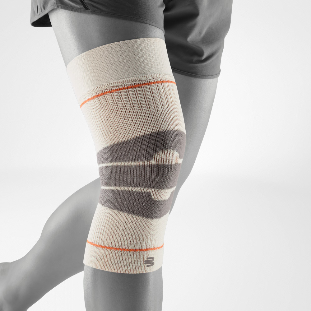 Kniebandage in Sandfarbe in seitlicher Ansicht. Deutlich sichtbar sind die anatomischen Zonen, die Halt und Schutz bieten, während das leichte Material volle Bewegungsfreiheit bei Outdoor-Aktivitäten gewährleistet.