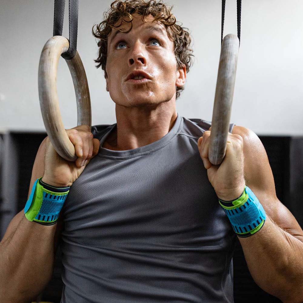 Handgelenkbandage rivera beim Fitness Mann mit Handgelenksbandagen zieht sich an Ringen in einem Fitnessstudio hoch