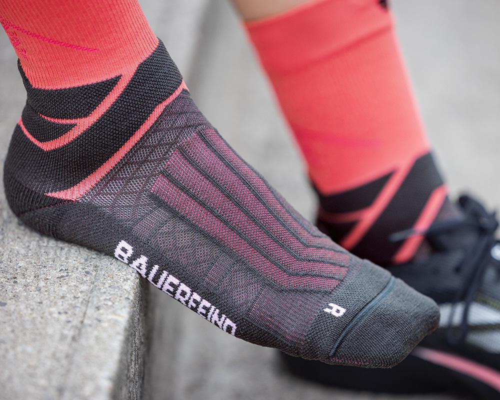 Mann mit grau-blauen Laufsocken schnürt seine Laufschuhe