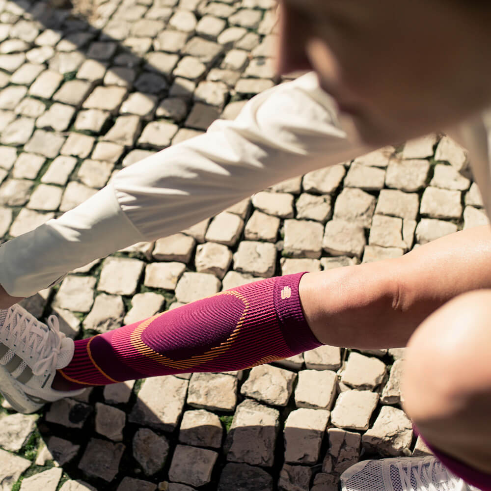 Läuferin dehnt ihre Wade mit langen Laufsocken in pink