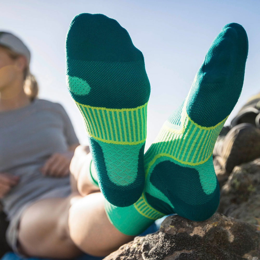Wanderin legt bei einer Pause die Beine hoch	 Fokus auf den grünen Trekkingsocken die sie trägt