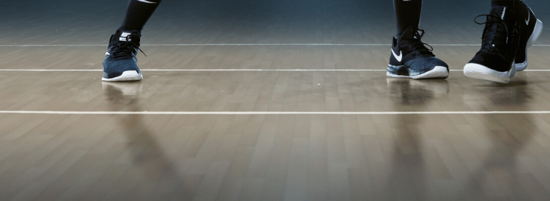 Blick auf den Fußboden einer Basketballhalle und die Füße von zwei Spielern