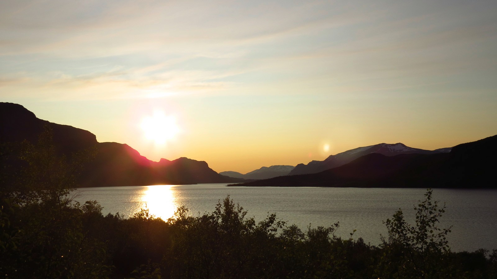 Panorama eines Sees mit Bergen bei Sonnenuntergang