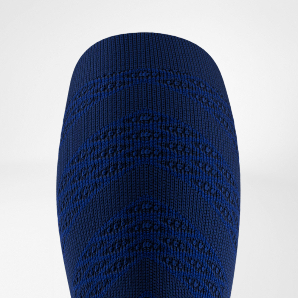 Nahaufnahme eines dunkelblauen Compression Sleeves mit markantem, strukturiertem Strickmuster in V-Form. Das enge Gewebe betont den sportlichen Look und unterstreicht die funktionelle Unterstützung für die Wadenmuskulatur.