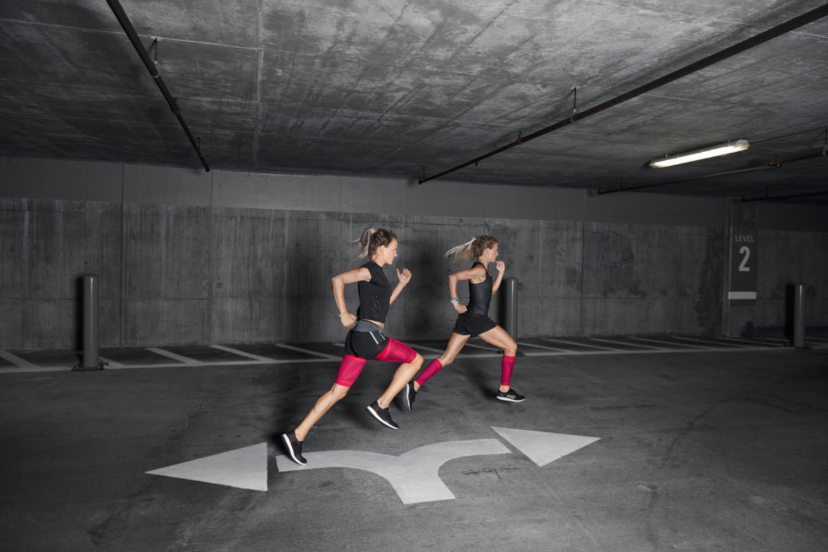 Zwei Läuferinnen mit pinken Compression Sleeves rennen durch ein Parkhaus