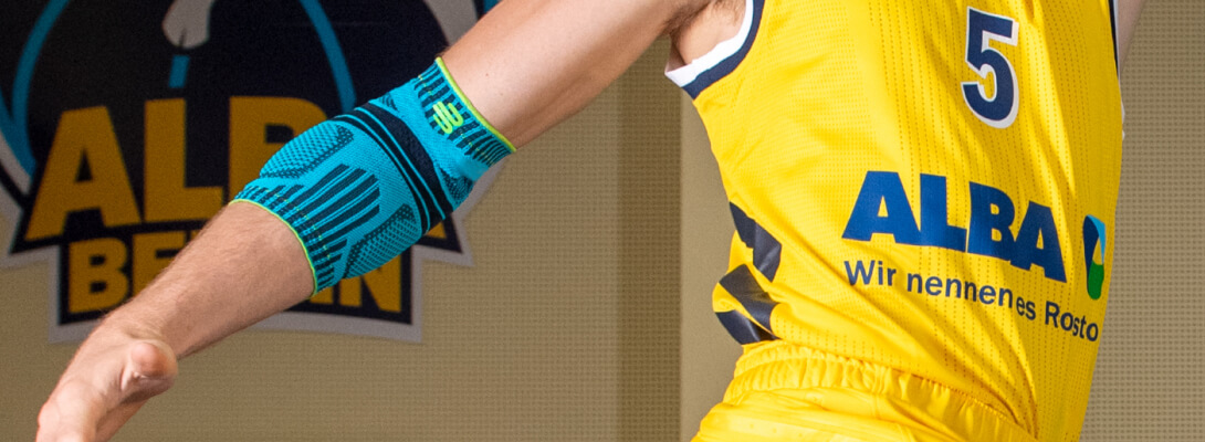 Basketballspieler mit Alba Berlin Trikot trägt eine Sportsbandage für den Ellenbogen
