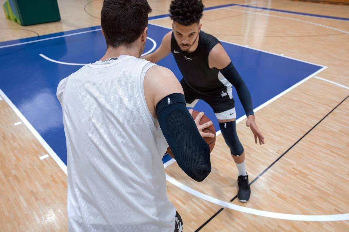 zwei Baskettballspieler auf dem Feld zwei Baskettballspieler spielen um einen Ball und tragen Armsleeve und Kniebandage