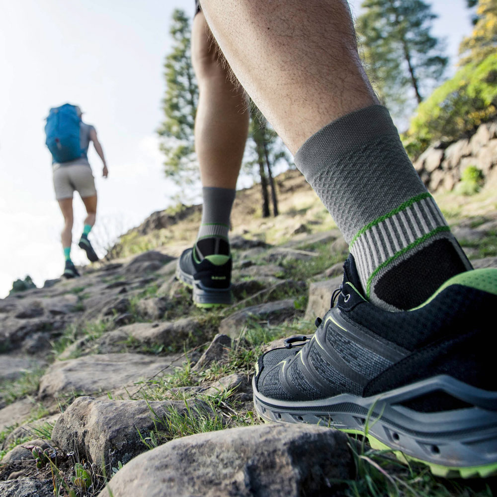 Wanderer mit grauen Trekkingsocken laufen einen Berg hoch	 Zoom auf die Socken