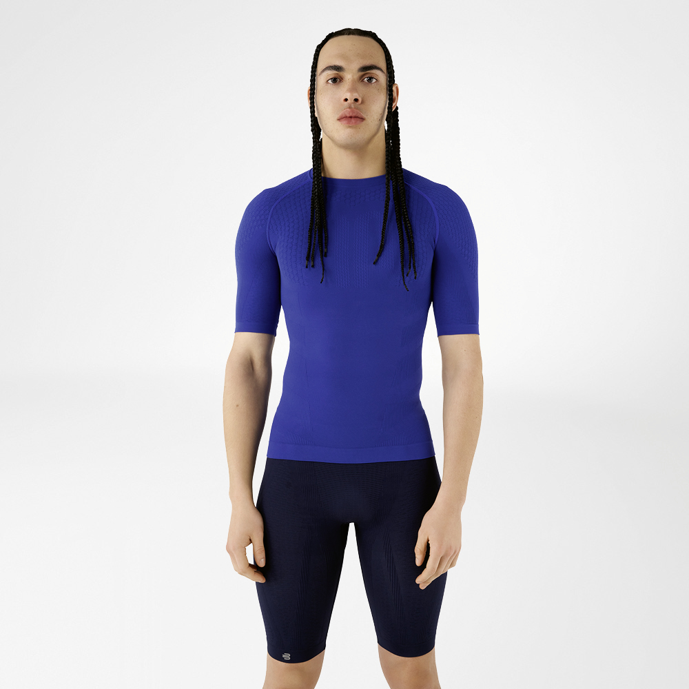 Mit unserer Kompressionskleidung bist du bereit für Bestleistungen Ein Mann in blauer Kompressionskleidung steht aufrecht und schaut in die Kamera.