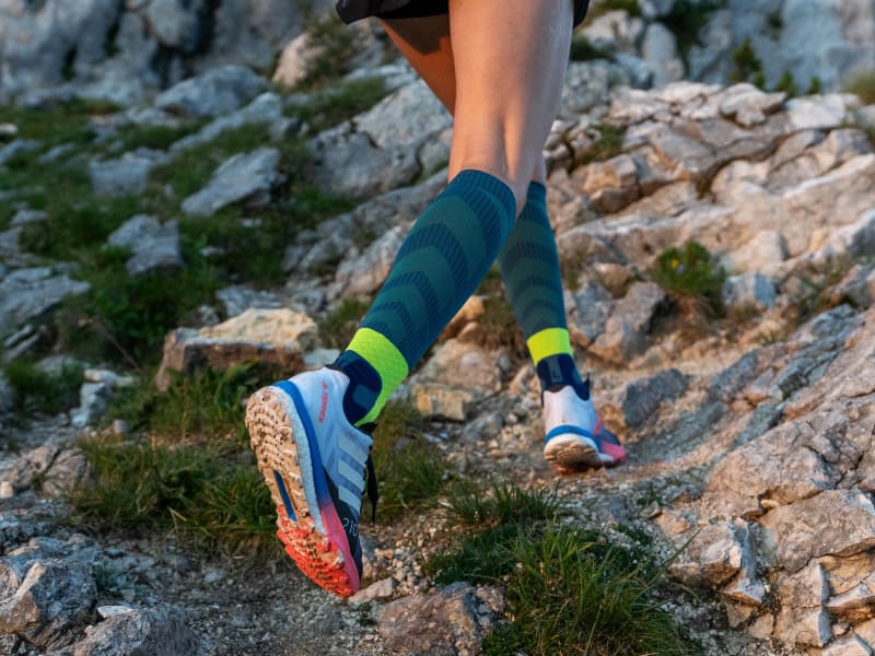 Läuferin läuft steinigen Bergabschnitt hoch und trägt Trail Run Socks
