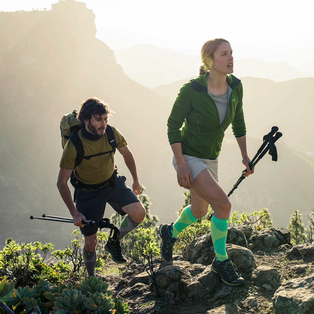 Zwei Wanderer die Kompressionssocken zum Wandern tragen laufen einen Berg hoch
