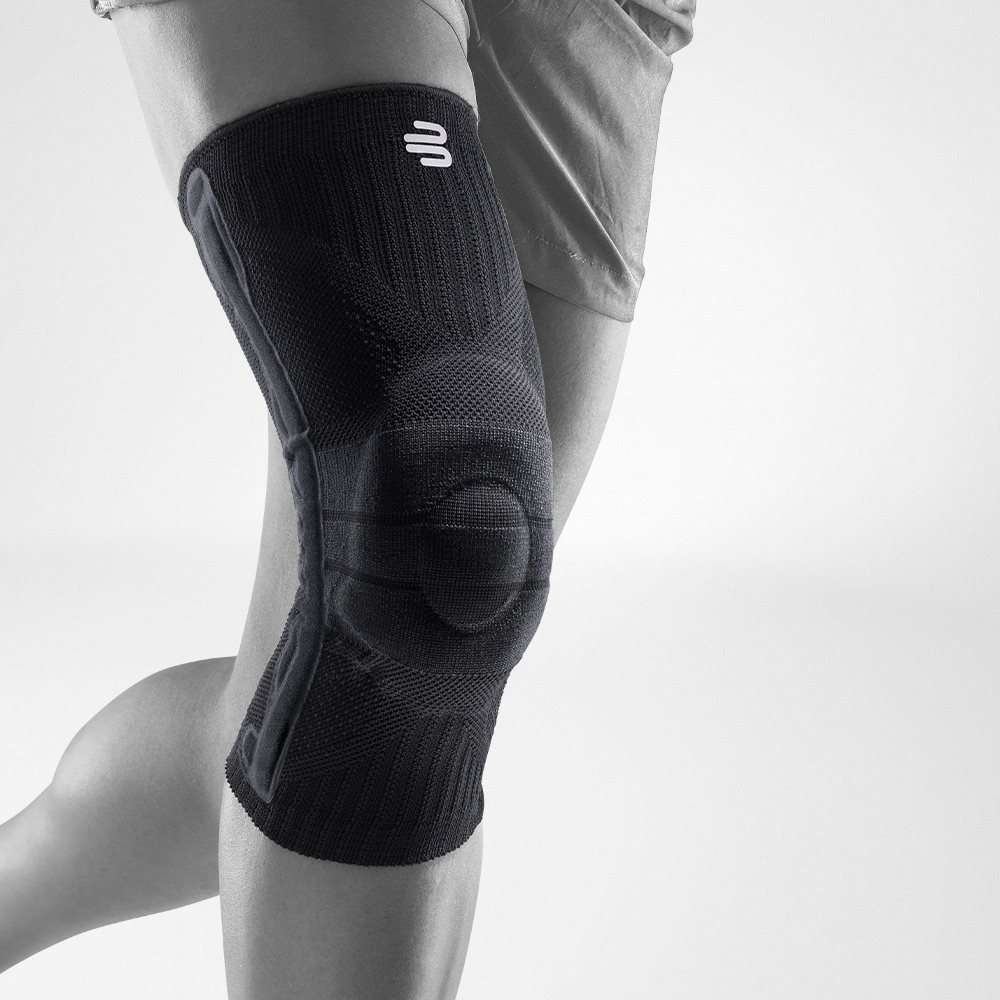 Kniebandage schwarz Vorderansicht schräg Komplettansicht einer schwarzen Kniebandage für den Sport am stilisierten grauen Bein