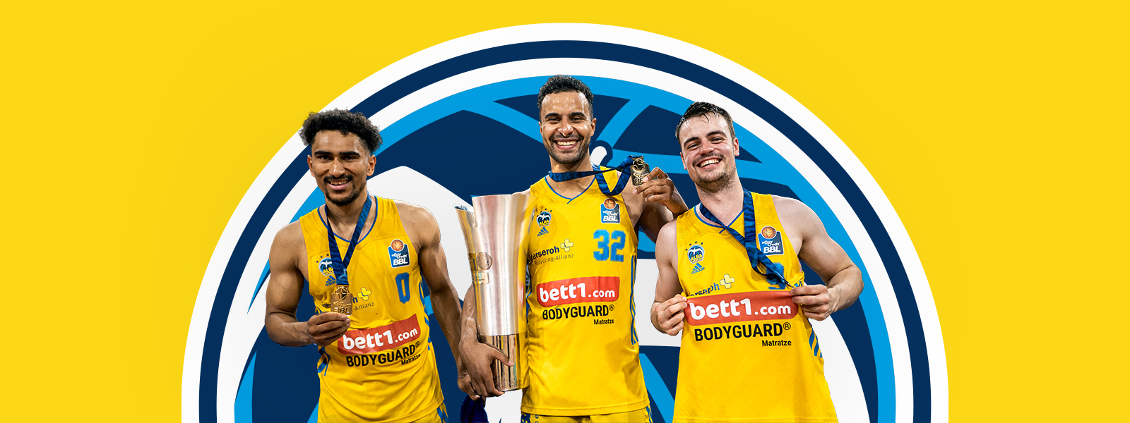 Drei Spieler von Alba Berlin mit Pokal vor einer gelben Fläche mit dem Alba-Berlin-Logo