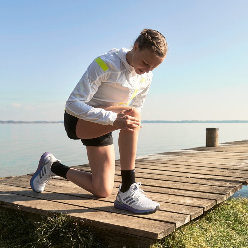 Läuferin Anna Hahner kniend am Steg hält sich das Knie